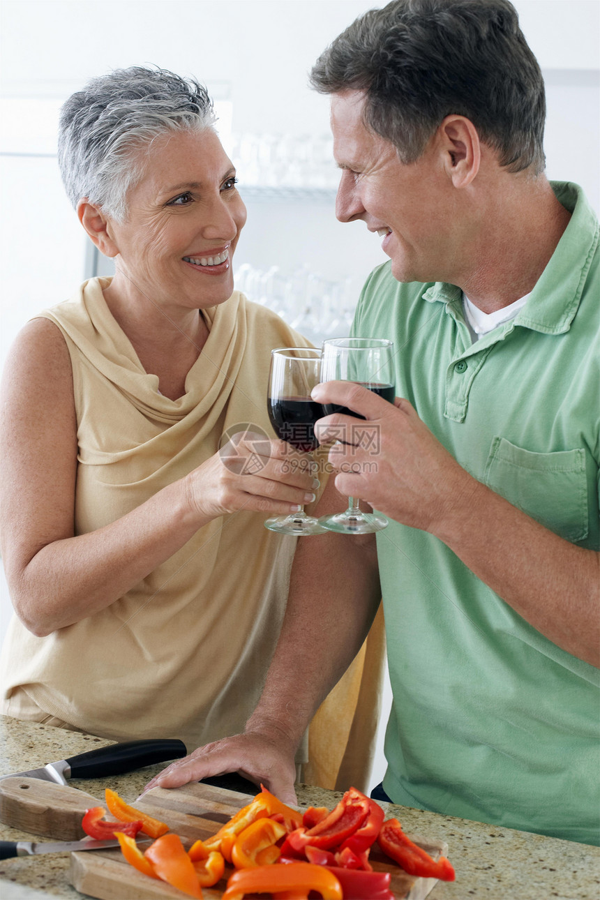年长夫妇一起站在一起 在厨房举酒杯图片
