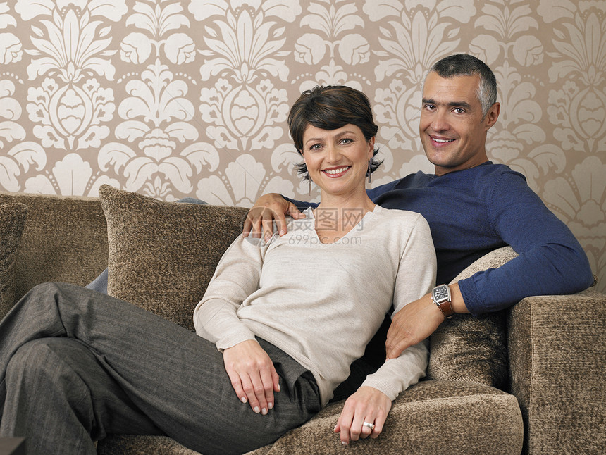 坐在沙发上的幸福情侣的肖像微笑房子感情异性丈夫男人婴儿夫妻成人女性图片