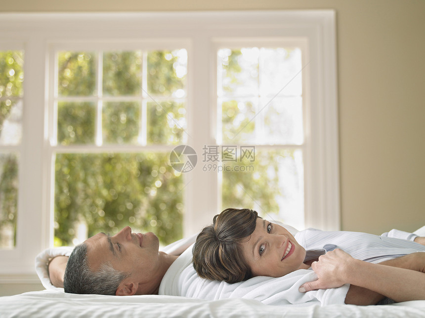和丈夫躺在床上的快乐女人的肖像图片