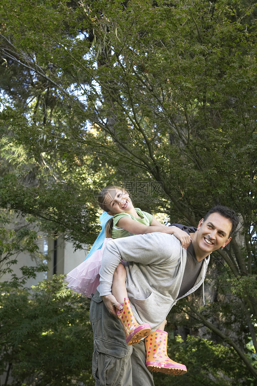 快乐的父亲搭载快乐的小女孩 在公园里图片