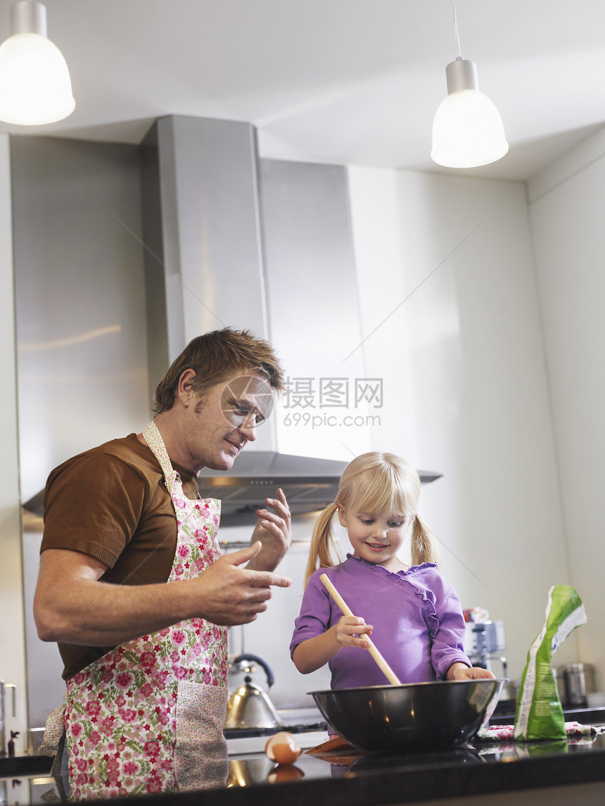 父亲帮助女儿在厨房里做饭图片