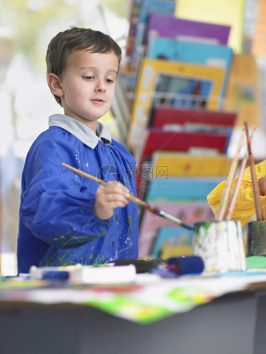 在艺术课上画油漆笔画的男孩图片