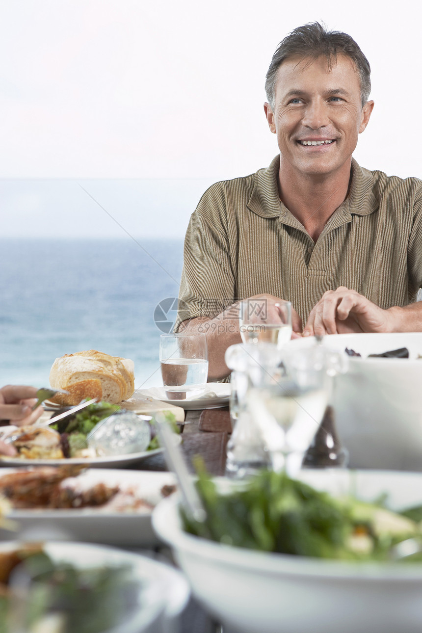 中年男子在海边吃饭时微笑图片