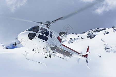 直升机飞越雪地山峰飞过白雪山峰背景
