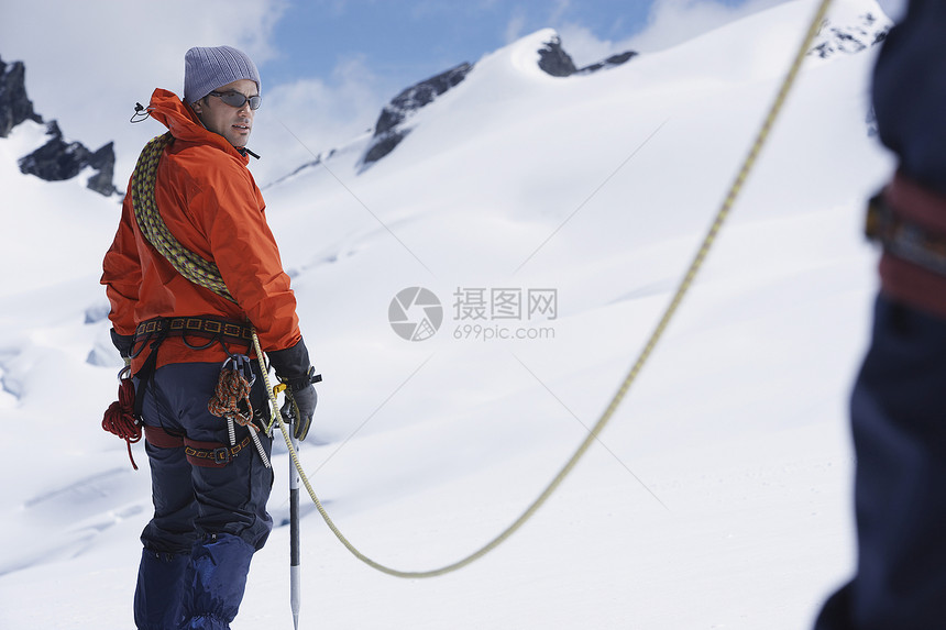 与雪山安全线相连的男性徒步旅行者图片