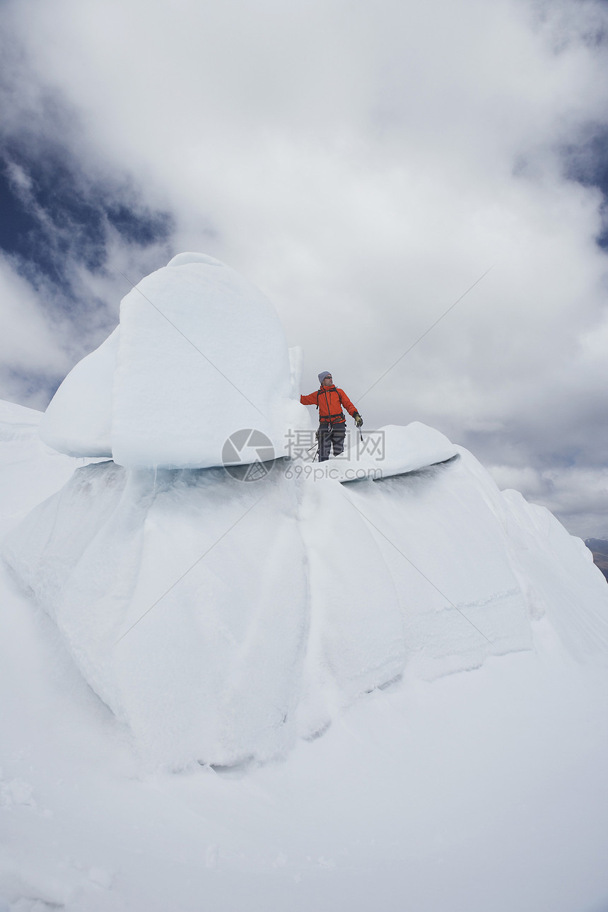 一只男性徒步者在冰层对云层形成顶端的低角度视图图片