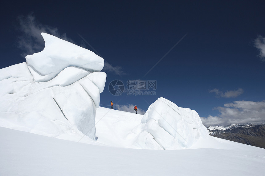 在雪山远处经过冰层的 两位徒步者的侧面景象滑雪闲暇男士上坡假期探索者勘探队形团队高度图片