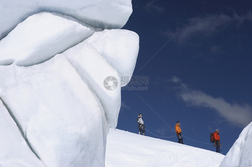 在雪山远处经过冰层形成 3个徒步登山者的侧面景色远足者旅行探索者滑雪勘探上坡活动远足娱乐闲暇图片