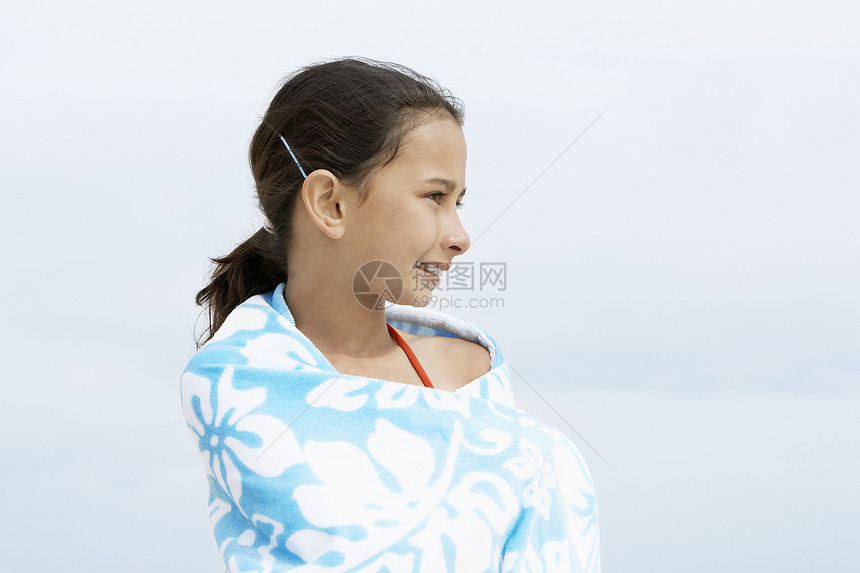 快乐的小少女 裹着毛巾的美少女 一边站在沙滩边 一边往远处看图片