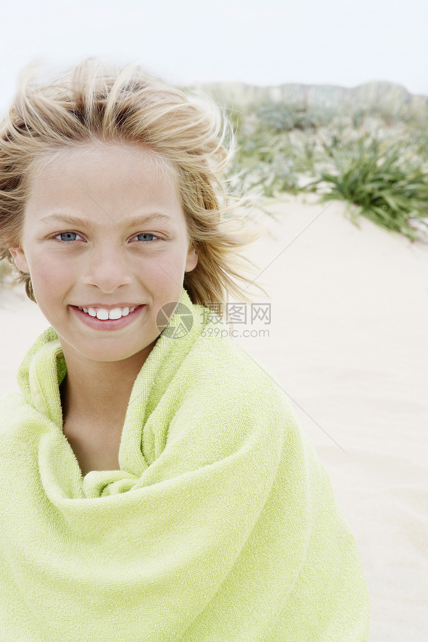 快乐的小男孩的肖像 用毛巾裹在沙滩上图片