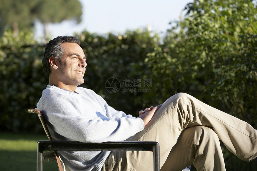 坐在后院椅子上的快乐男人的侧景图片