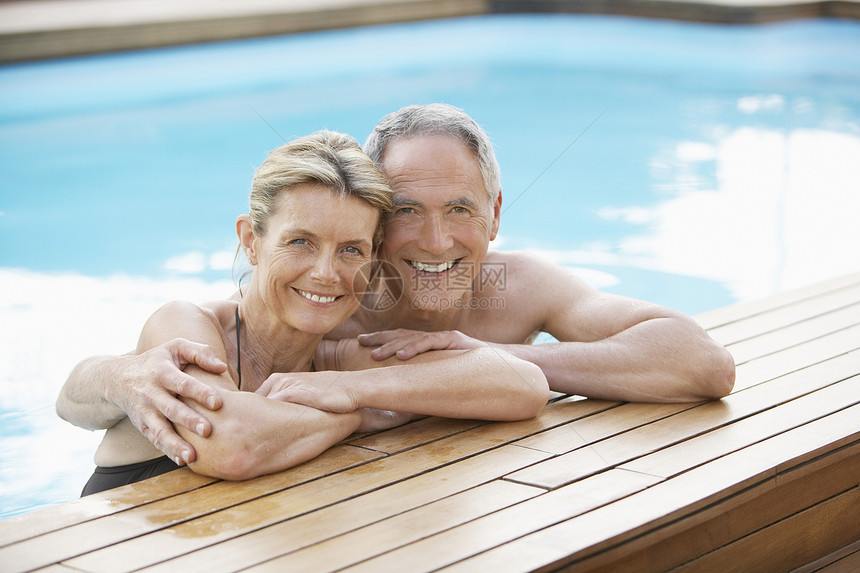 快乐的中年夫妇在游泳池边缘放松时的肖像享受娱乐夫妻团结女性甲板男人木头闲暇假期图片