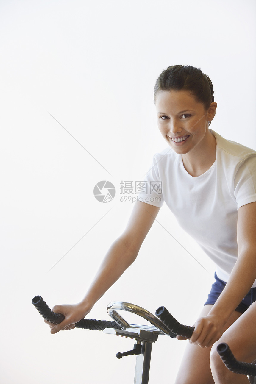 微笑着的年轻女子在白色背景上练习自行车训练的肖像图片