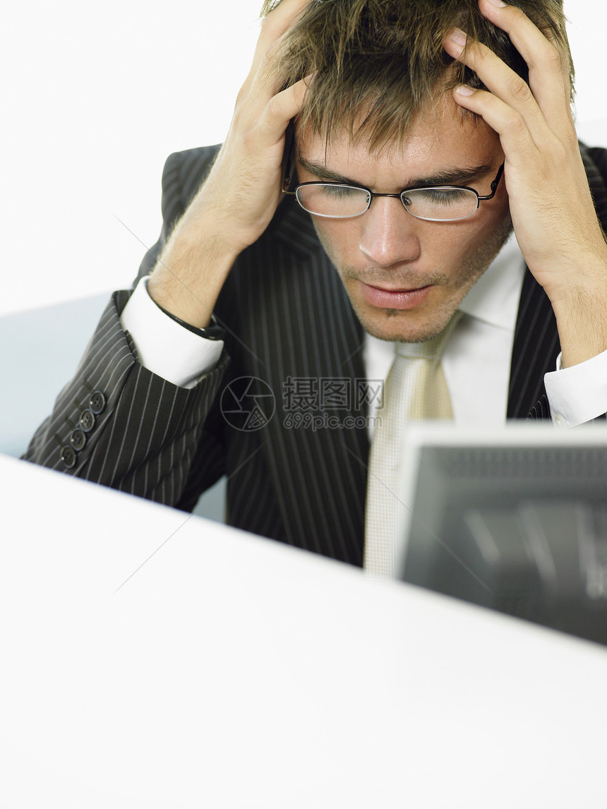 坐在计算机服务台的有压力的年轻商务人士;图片