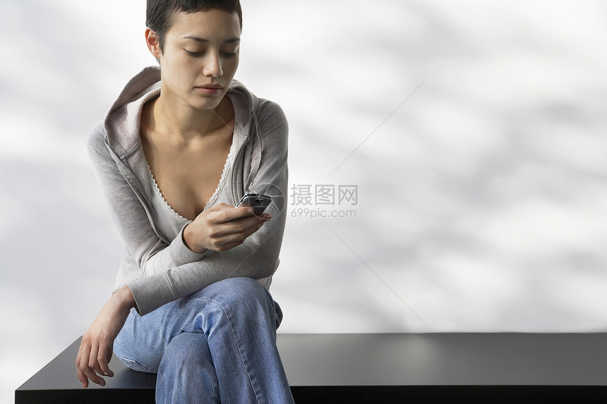 美丽的年轻女子在室内长椅上阅读短信图片