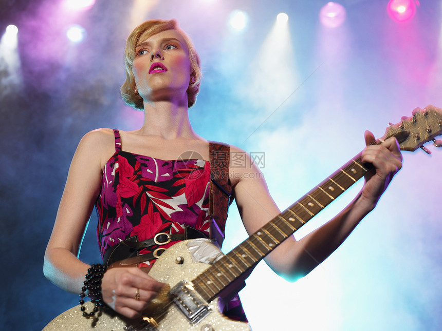 女摇滚吉他手在演唱会舞台上的低角度视角图片