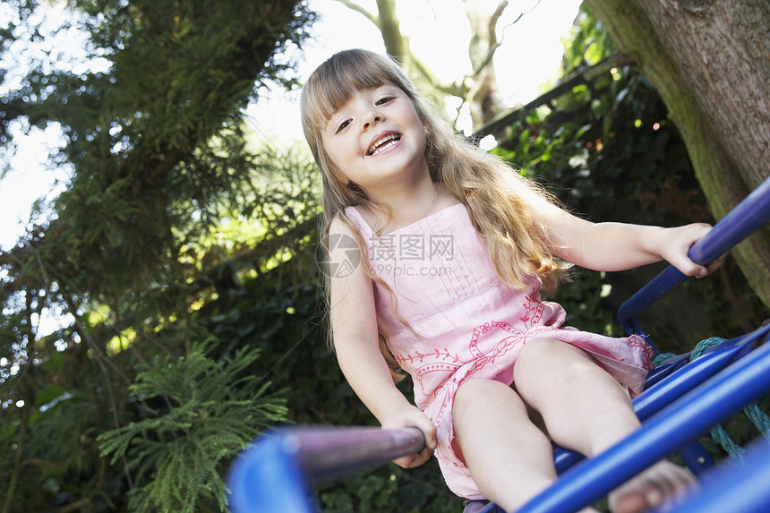 坐在后院猴子棍上的一个年轻女孩的肖像图片