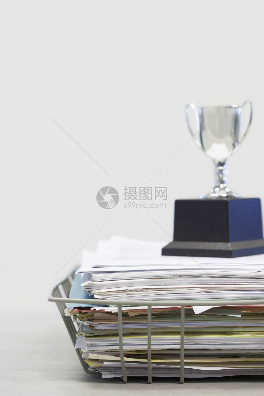 白色背景上的文件文件夹堆叠上的奖杯图片