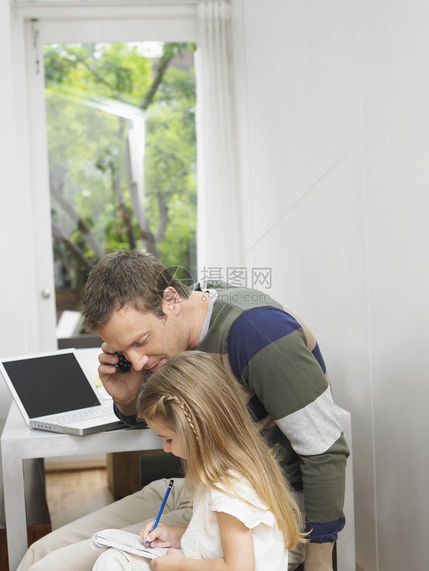 当他看着女儿做功课时 拿着笔记本电脑的年轻人图片