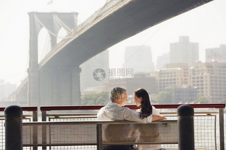 一对夫妇在布鲁克林桥下 放松板凳的近视图片