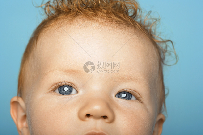 红发可爱婴儿的特写肖像 蓝背景被孤立图片