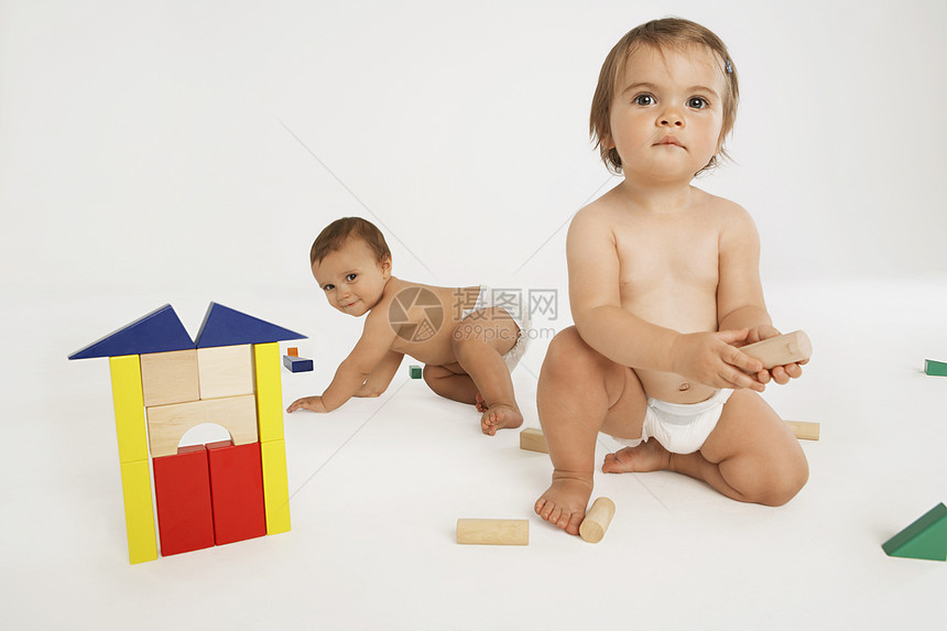 以白色背景孤立的建筑构件玩游戏的女婴和男婴图片