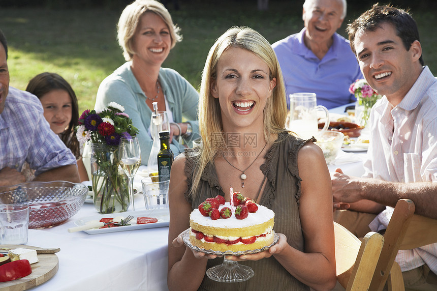 家庭在户外餐桌上的室外妇女持有草莓蛋糕图片
