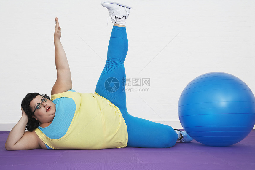 超重妇女通过锻炼 在卫生中心伸展手臂和腿向上躺着图片