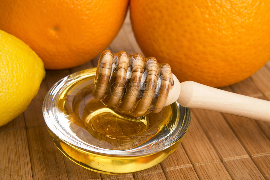 含柠檬和橙子水果的新鲜蜂蜜早餐生活方式勺子健康饮食液体金子木头餐具美食家甜点图片