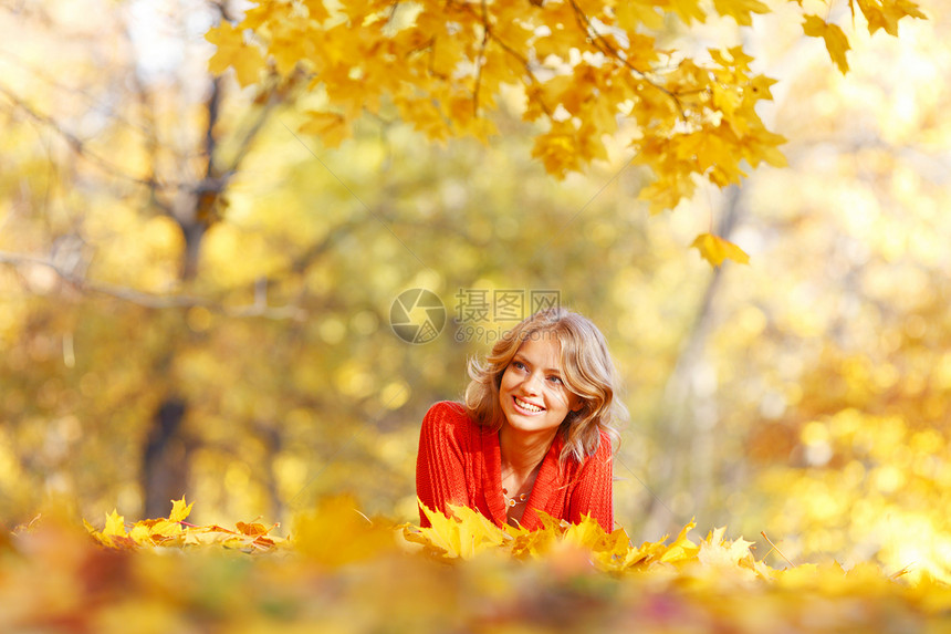 女人躺在秋叶上乐趣微笑红色幸福橙子喜悦公园女性女孩金子图片