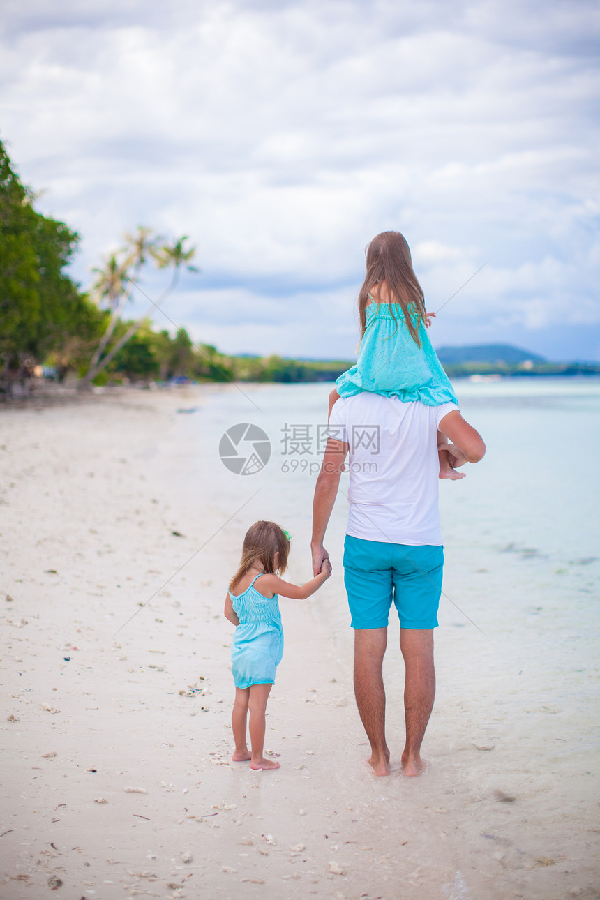 在热带白沙滩上看到爸爸和两个孩子的近视图片