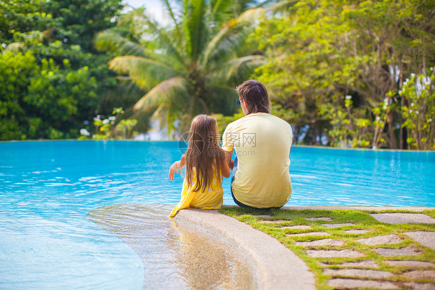 坐在游泳池旁边的年轻父亲和可爱女儿的后视景色活动乐趣喜悦成人假期家庭太阳闲暇童年婴儿图片