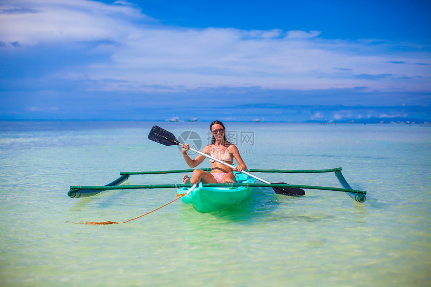可爱的小可爱女孩在清澈的蓝海中划皮艇天空阳光独木舟闲暇海洋活动姿势运动小艇血管图片