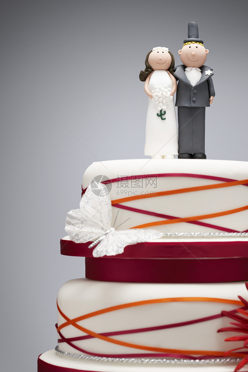 喜剧新娘和新郎在婚礼蛋糕上面的雕像图片