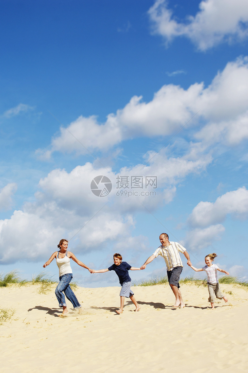 整个幸福的一家人手牵手 在沙滩上跑下沙丘海滩孩子男生女儿父亲牛仔布孩子们女孩短裤赤脚图片