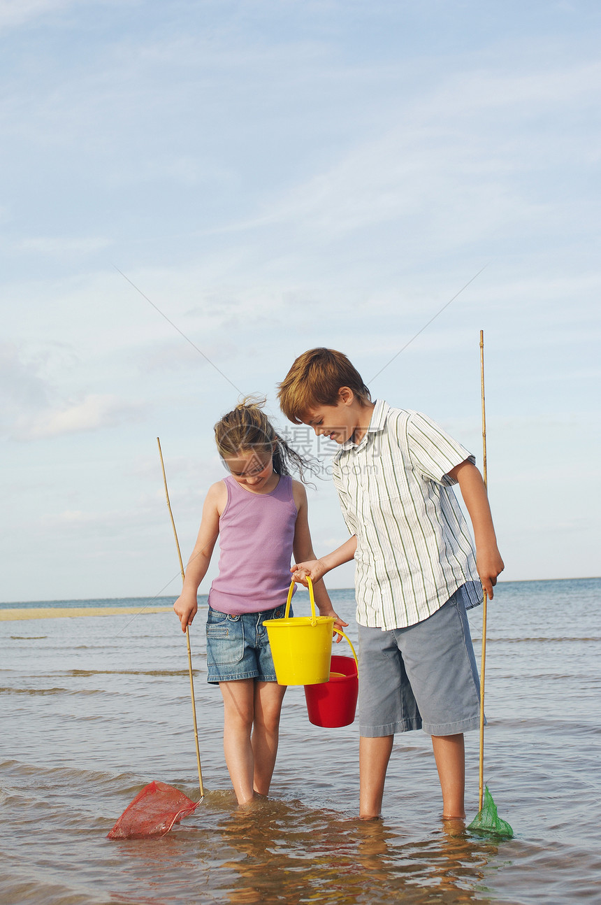 哥哥和姐姐在海滩上冲浪 用水桶和小鱼网图片