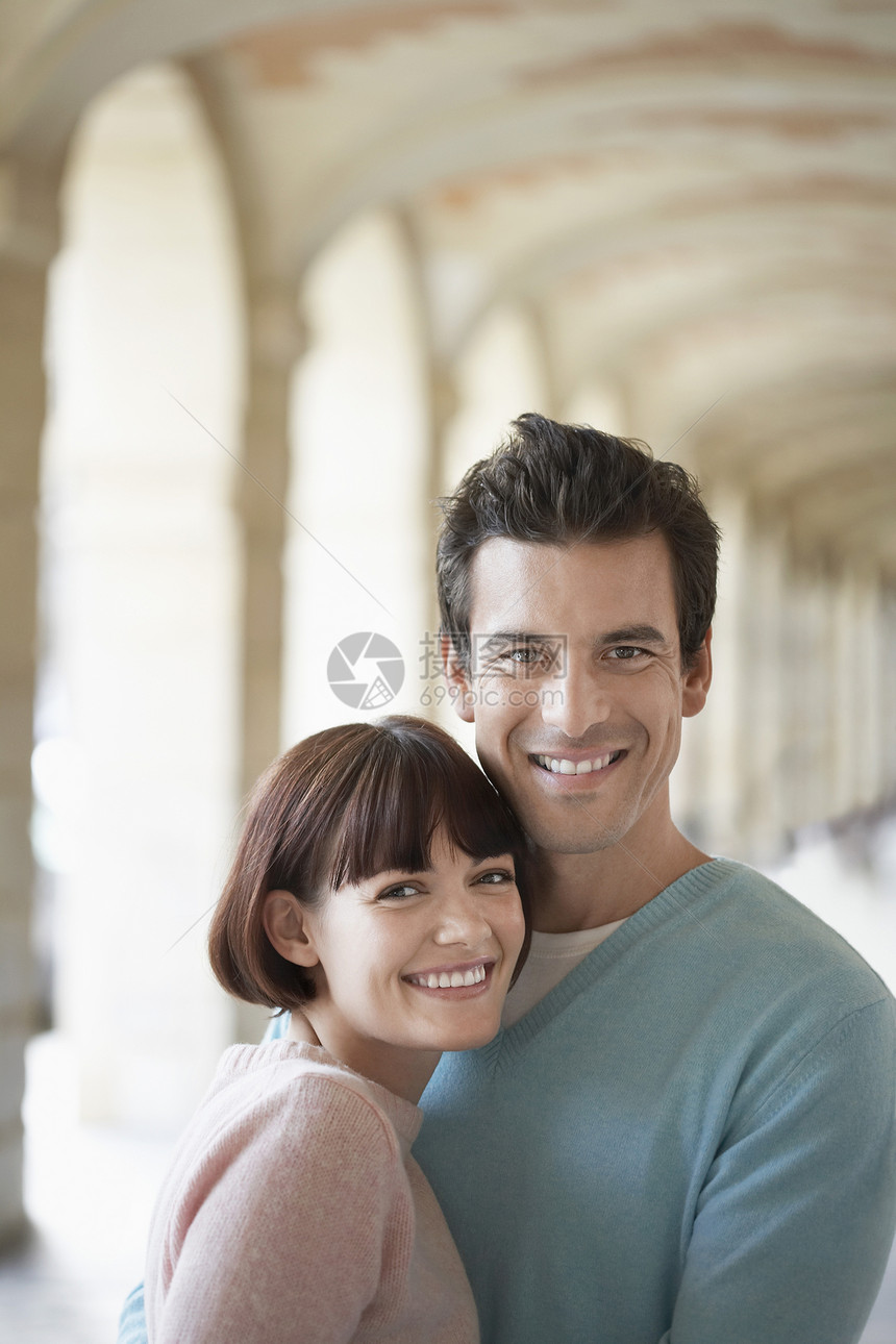 一个微笑的年轻夫妇 拥抱在拱门下面的近距离肖像图片