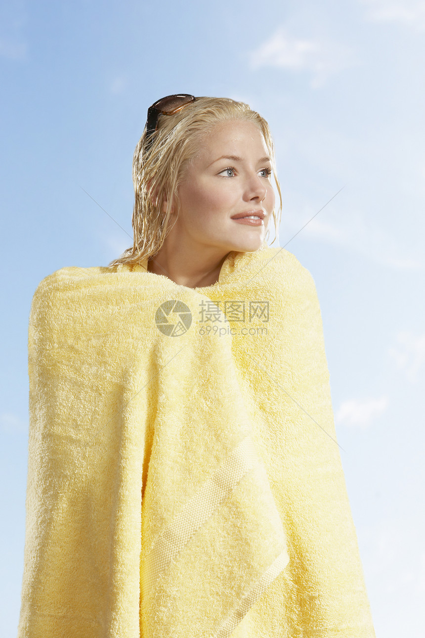 美丽的年轻姑娘 在阳光明媚的一天 用黄毛巾包在天上图片