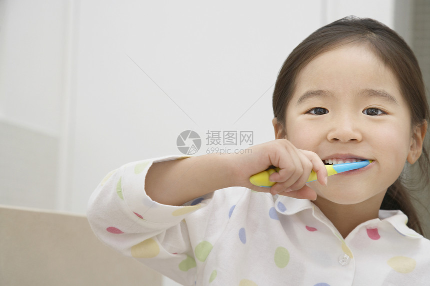 一位年轻女孩刷牙的近镜肖像图片