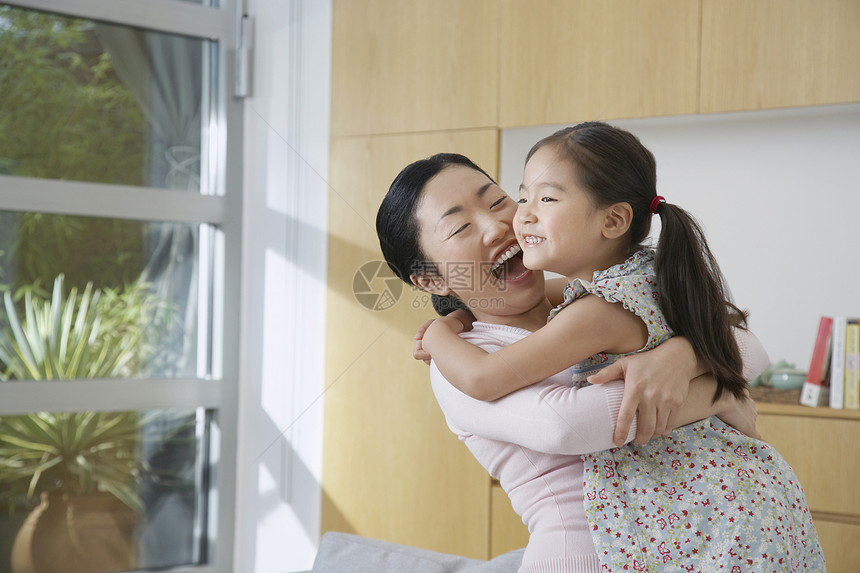 在客厅里拥抱她女儿的 开心的女人图片