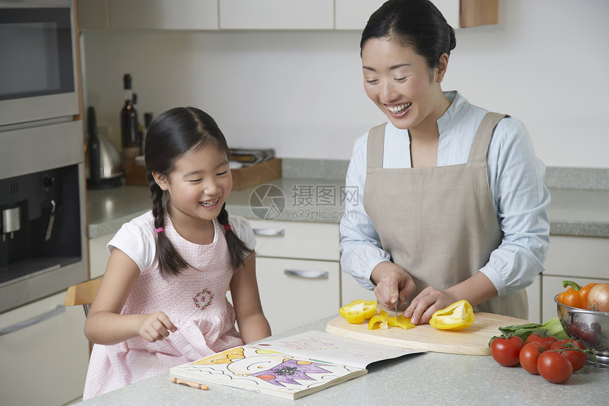 女儿在厨房柜台上彩色 母亲在厨房里切胡椒图片