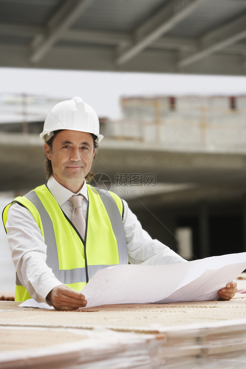 一名男性建筑工人的肖像和现场有蓝图的男性建筑工人图片