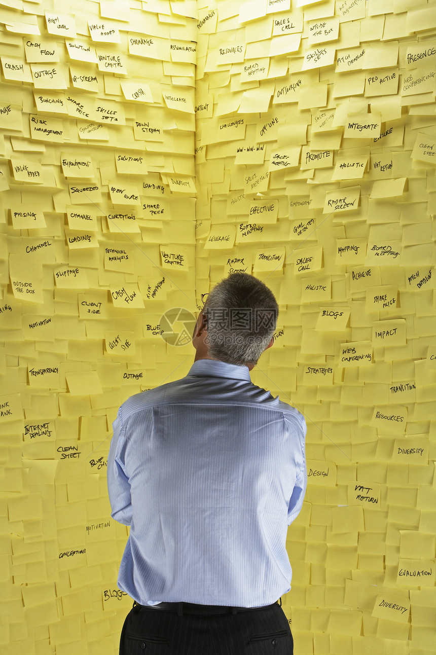 一名商务人士站在墙前 贴着粘黏纸条的一面后视线健忘男人房间压力正装笔记纸职业思维材料商业图片