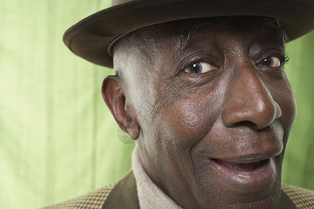 一名身戴帽子顶着绿幕的非裔美国人高官的近视肖像退休工作室幸福男士窗帘绿色老年祖父花花公子背景背景图片