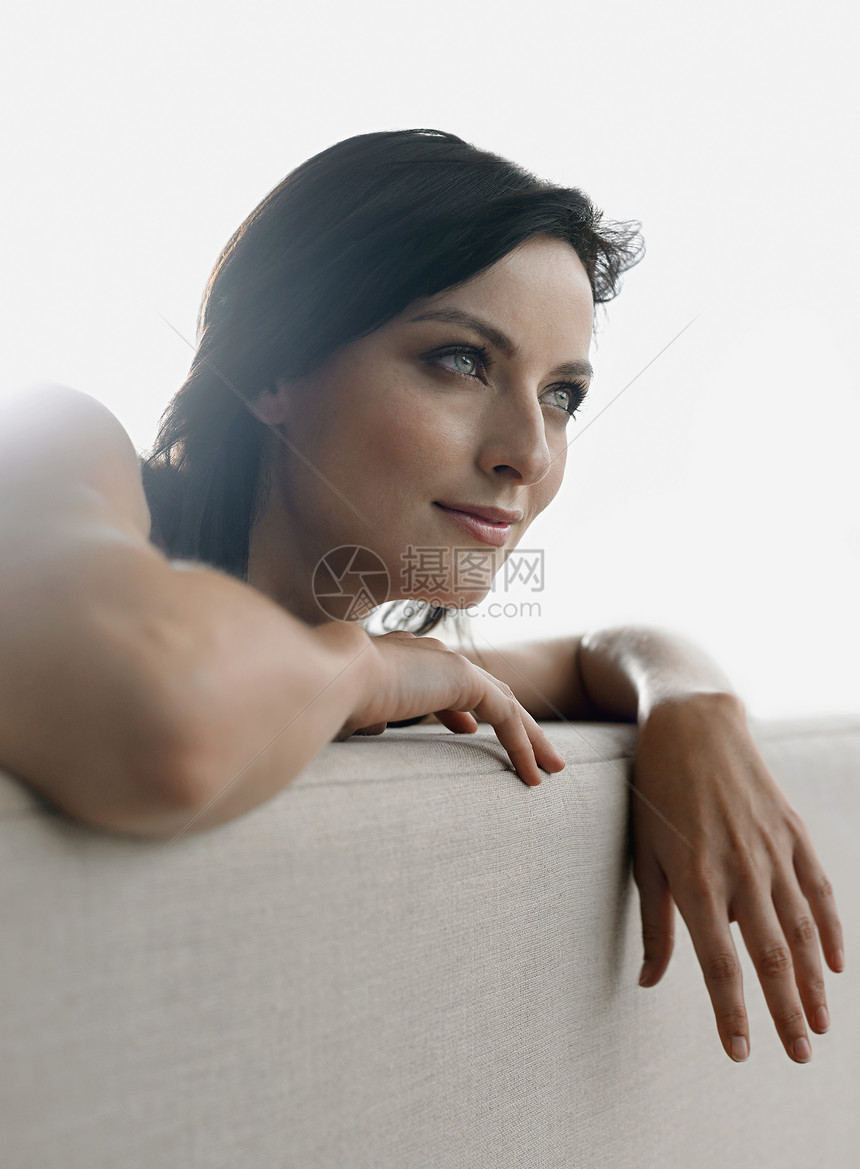 在沙发上靠着一个美丽的年轻女孩的近身长椅思维倾斜阳光成人视图女性闲暇沉思女士图片