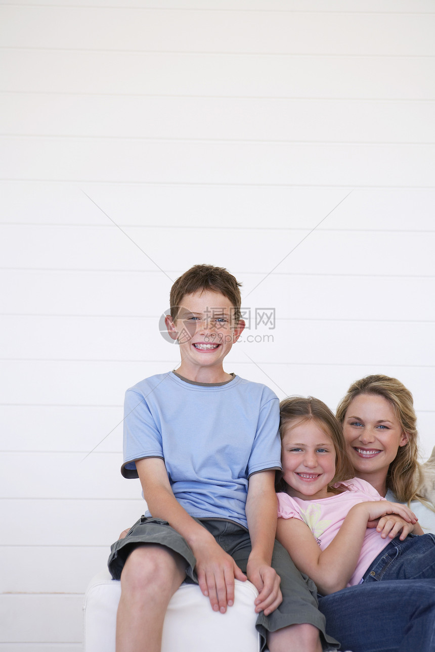 喜悦的年轻男孩的肖像 母亲和姐姐坐在沙发上图片