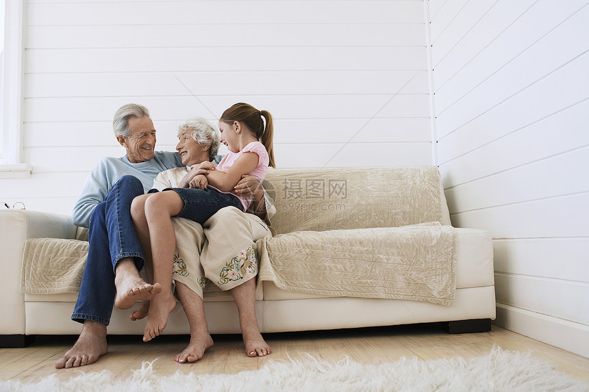 坐在沙发上和孙女一起坐着的一对幸福的老年夫妇图片