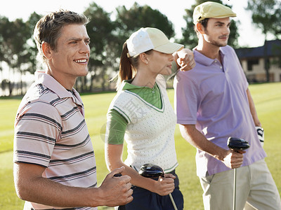 三名青年高尔夫球员站在高尔夫球场上背景图片