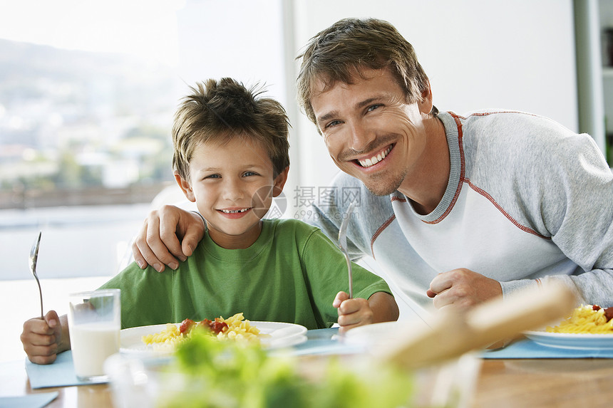 快乐的父亲和儿子在餐桌上共进早餐的肖像图片
