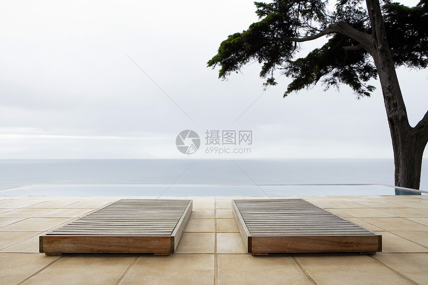 两张太阳床 由无尽游泳池铺成 俯视海边的两张阳光床图片